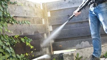 power washing a commercial fence along business walkway