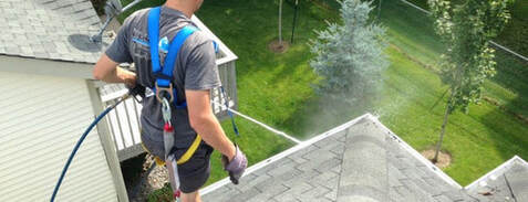 cleaning the gutters of a home in bonita springs with a pressure washer