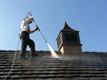 professional pressure washing company employee on top of a commercial roof getting it cleaned